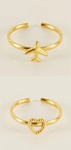 Detail of gold plane and heart rings with adjustable bands and polished finish