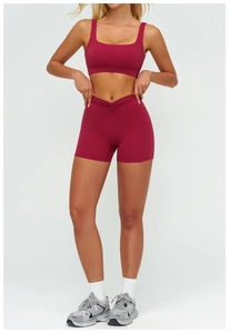 Dettaglio degli shorts da yoga a vita alta plissettati e del reggiseno sportivo rosso bacca