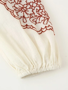 Detailed macro view of embroidered floral pattern on white linen sleeve with elastic cuff