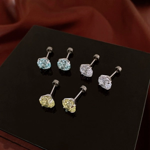 Macro shot of three pairs of round-cut zircon stud earrings in blue, white, and yellow