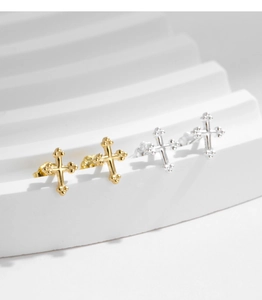 Detailed view of minimalist gold and silver cross stud earrings on white display