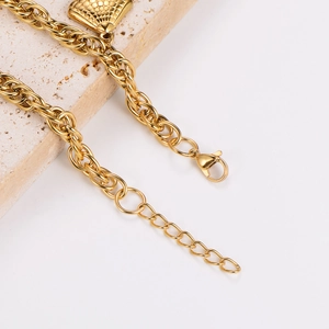 Detailed macro view of gold lobster clasp, extension chain, and textured square pendant