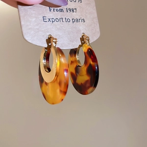 Detail of tortoise shell acetate earrings with sunburst engraved gold metal plating