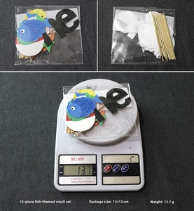 Detail view of 12-piece fishing theme cake toppers showing package size and weight on scale