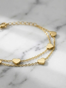 Close-up of golden double-layer heart bracelet with lobster clasp on marble background