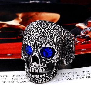 Macro shot of gothic silver skull ring with blue gemstone eyes and intricate carvings