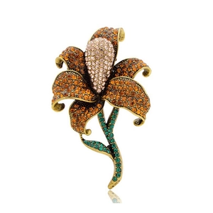 Vintage lily flower brooch with amber rhinestones and emerald crystals on white background