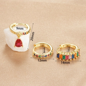 Macro detail of three 18k gold plated rainbow gemstone earrings on champagne silk fabric