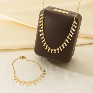 Detail of gold necklace and bracelet set with pink beads and water drop pendants