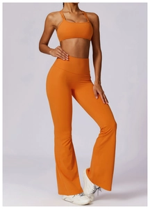 Macro detail of orange high-waisted flared yoga pants and slim double-strap sports bra