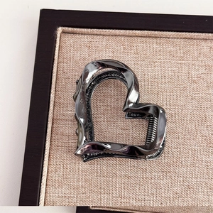 Detailed view of gunmetal heart-shaped metal hair claw clip on brown fabric base