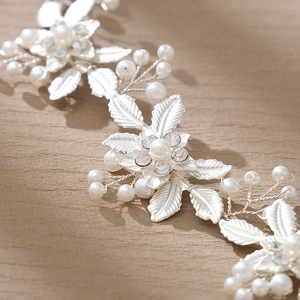 Silver bridal headband with floral leaf design, pearls and rhinestones on beige fabric