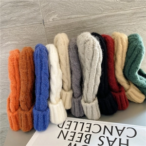 Detail view of thick cable knit beanies in various colors including orange and blue