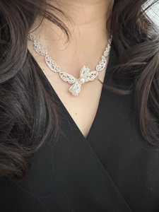 Détail du collier en dentelle avec pendentif nœud et perle blanche sur un mannequin