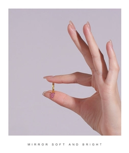 Detail view of gold heart earrings with sparkling pink zircon crystals held in hand