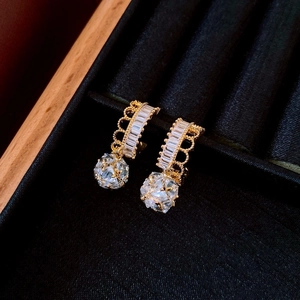 Detailed macro of golden crown earring with zircon stone in a black velvet jewelry box