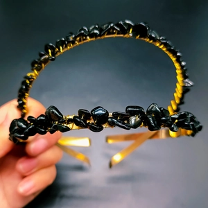 Macro detail of hand-wrapped gold wire crown headband featuring raw black crystals