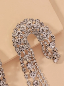 Detailed view of silver asymmetric U-shaped earrings with cascading rhinestone tassels