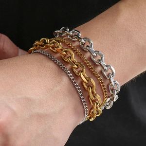 Detail of layered gold and silver stainless steel chain bracelets for men on wrist