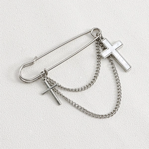 Detail of silver cross brooch with white shell pendant and elegant metal tassel chains