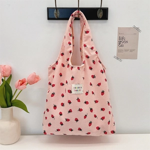 Sac cabas en velours côtelé rose avec imprimé fraises accroché à un crochet