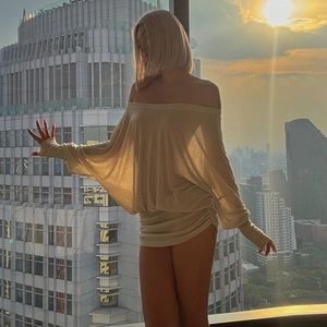Close-up of beige off-the-shoulder mini dress with ruched details and long sleeves