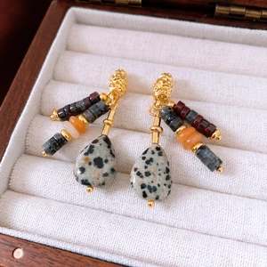 Close-up of vintage beaded drop earrings with spotted stone on white velvet display