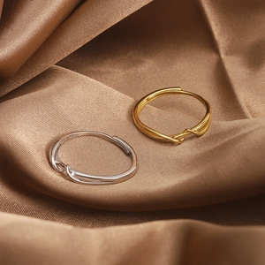 Close-up of gold and silver S925 sterling silver twisted rings on brown silk fabric