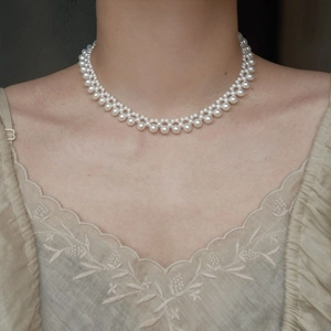 Close-up of double-layer woven pearl choker on model wearing embroidered V-neck top