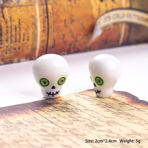 Macro view of 2cm skull charm beads with green eyes and black stitched mouth details