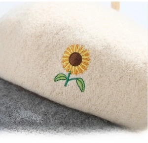 Close-up of vibrant sunflower embroidery detail on high-quality wool felt beret fabric