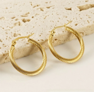 Close-up of golden twisted rope hoop earrings with detailed metallic spiral texture