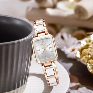 Detail of rose gold square watch with white ceramic band and diamond markers on a white disk