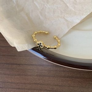 Elegant 925 sterling silver gold ring with black cross design on ceramic background