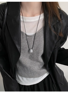 Detail of silver oval pendant with black wax cord shown on model for length scale