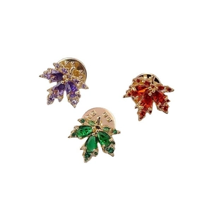 Detailed close-up of maple leaf brooches in three vibrant zircon colors on gold metal