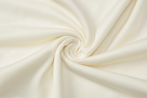 Macro shot of ivory knitted fabric showing high-density texture and soft drape detail