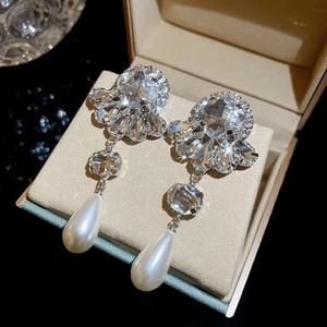 Macro shot of silver flower earrings with zircon crystals and teardrop pearl drops
