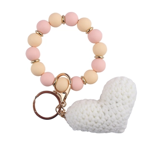Detailed shot of pink silicone beads bracelet with white crochet heart and gold keychain