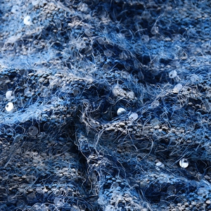 Detailed macro shot of blue sequined mohair fabric with shimmering metallic textures