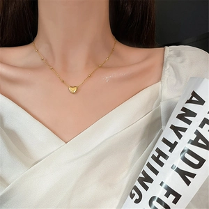 Elegant gold heart pendant necklace on model showing minimalist clavicle chain style