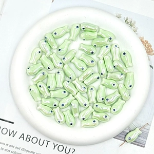 Macro view of light green fish-shaped ceramic beads for DIY jewelry making and crafts
