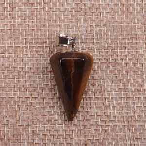 Detail shot of tiger eye stone hexagonal pillar pendant on textured linen background