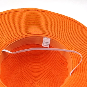 Orange summer straw sun hat showing interior paper fiber weave and windproof strap