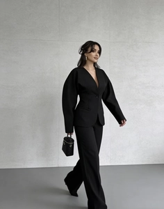 Détail d'un élégant blazer noir à col en V profond avec ceinture et pantalon large assorti