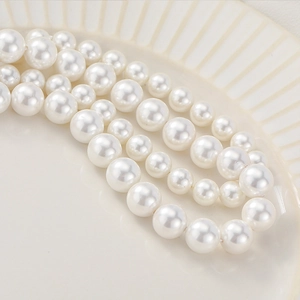 Elegant natural shell pearl strands in white finish displayed on a textured ceramic plate
