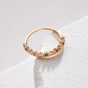 Close-up of 18K gold plated ring with rainbow zircons on white textured stone