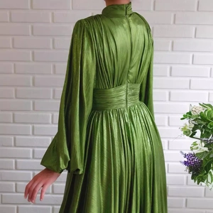 Elegant avocado green long sleeve pleated dress with a high collar and lantern sleeves