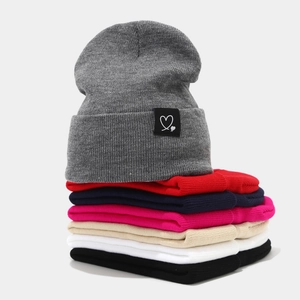 Bonnet en tricot gris avec logo cœur, présenté avec divers coloris hivernaux