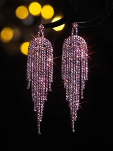 Macro detail of luxury long tassel earrings with sparkling pink and purple crystals